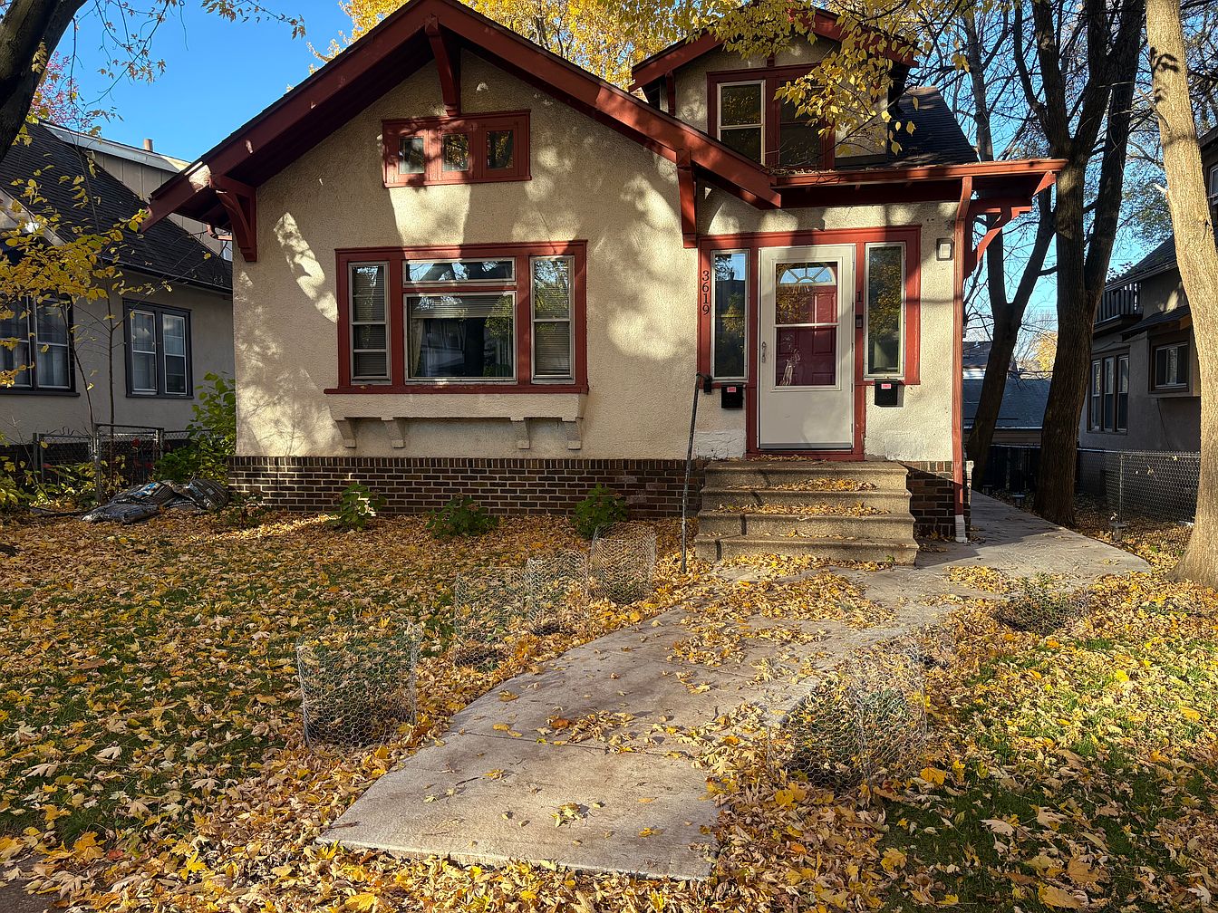 Cream stucco home with red trim and autumn leaves in Minneapolis